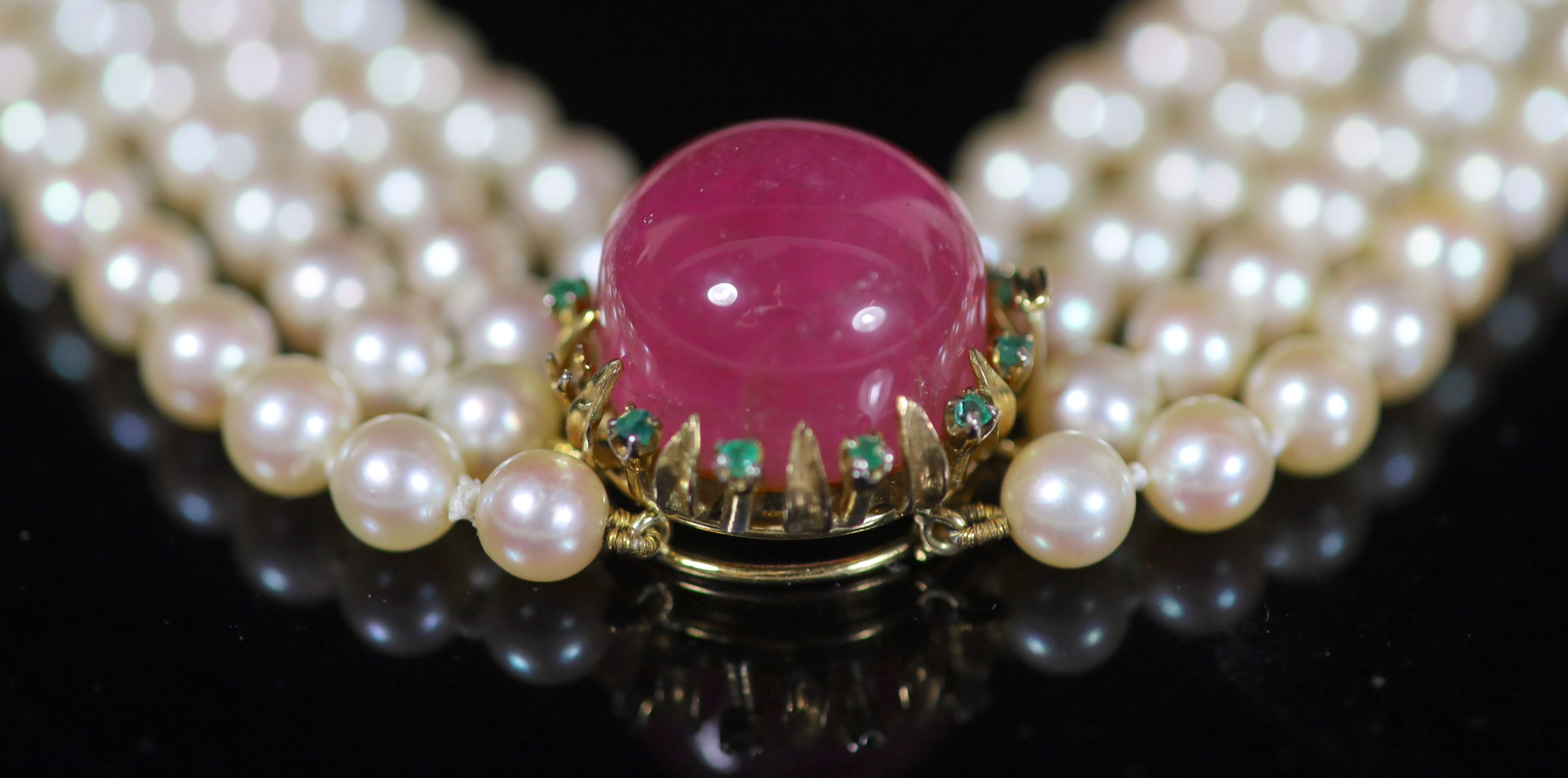 A four-strand graduated cultured pearl choker with circular cabochon pink tourmaline and emerald yellow metal clasp,